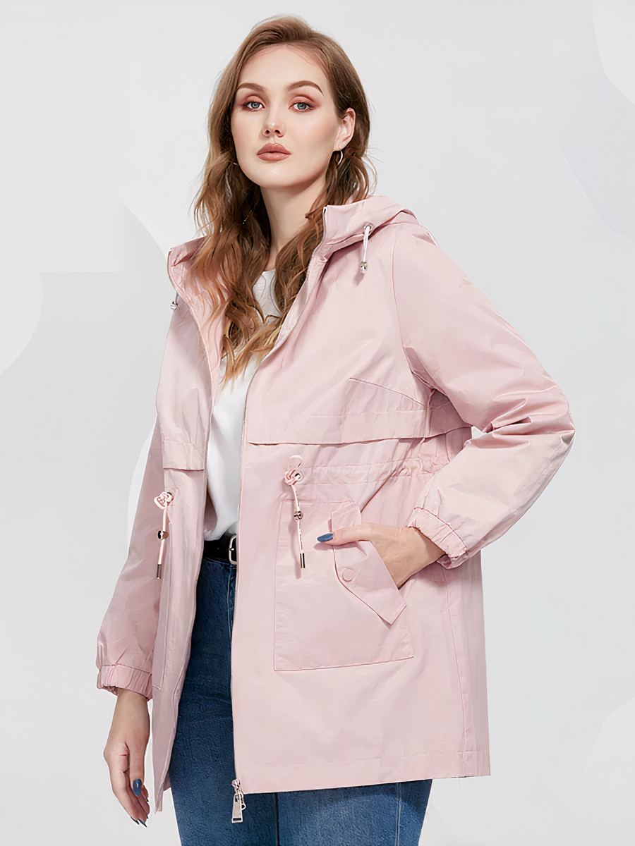 0-be671b.jpeg Veste parka femme conception coupe vent avec capuche, de couleur rose, porté par une femme sur un fond gris.