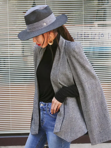Veste cape femme conception ample et élégante grise, porté par une femme avec un chapeau.
