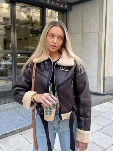 Veste courte femme en simili cuir marron foncé, avec col à revers en polaire blanc, porté par une femme dans la rue.