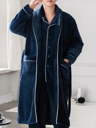 Veste d'intérieur homme style peignoir avec pantalon et chemise portée par un homme dans une maison avec une table et un échiquier à gauche et un meuble blanc derrière lui