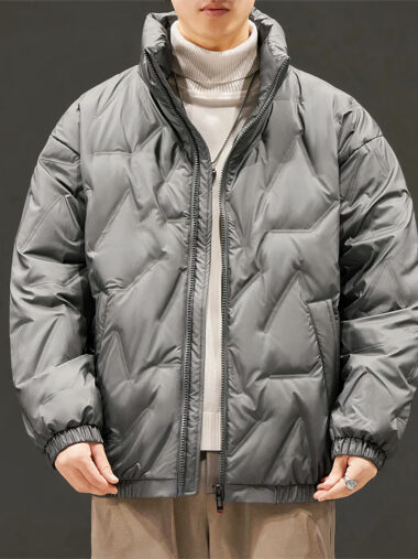 Veste doudoune homme large et coupe-vent portée par un homme avec un pull blanc et un pantalon marron sur fond gris