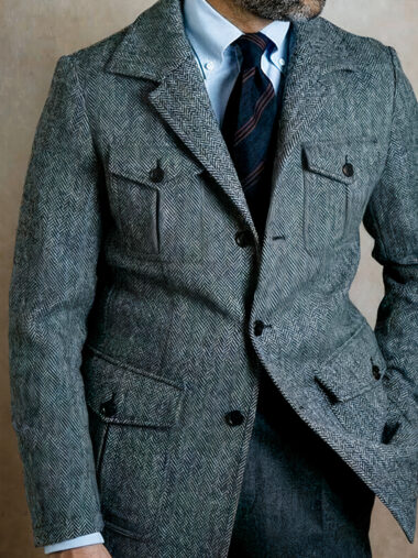 Veste habillée homme style homme d'affaires avec multi poches de couleur grise. Porté par un homme sur un fond marron.