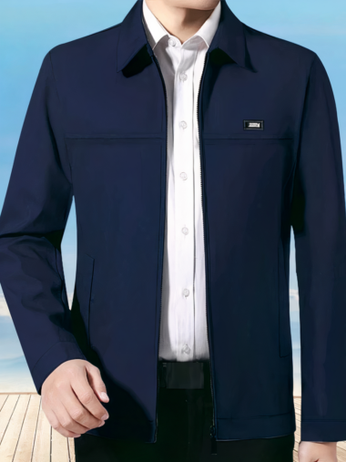 Veste légère homme style décontracté avec col rabattu portée par un homme avec une chemise blanche et un pantalon noir sur fond bleu et beige