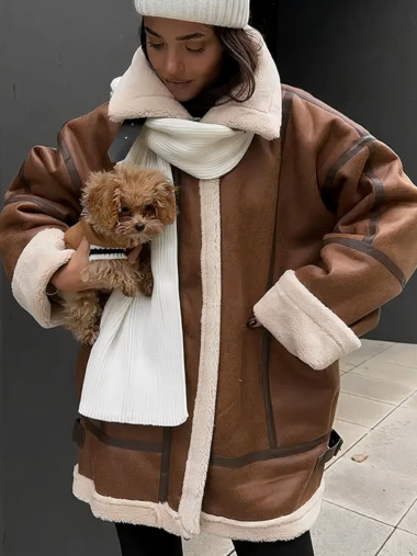 Veste moumoute femme large style décontracté portée par une femme avec un bonnet et une écharpe blanche et un pantalon noir qui tient un chien dans la rue