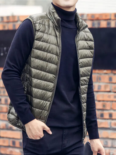Veste sans manche homme matelassée avec col haut, de couleur vert kaki. Porté par un homme, sur un fond de style mur en brique.