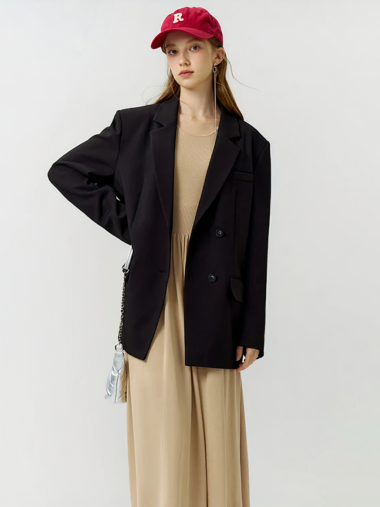 Veste tailleur femme noire et classique sur une femme debout avec une casquette rouge