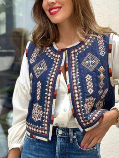 Veste patchwork sans manche avec broderies fleuries, de couleur bleu, porté par une femme.