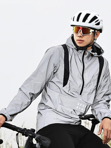 Veste vtt homme coupe-vent et imperméable, de couleur grise, porté par un homme sur son vélo, sur un fond blanc.