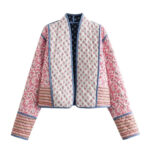 Veste patchwork conception matelassée et réversible, de couleur rose et blanche, avec des motifs fleuries, sur un fond blanc.