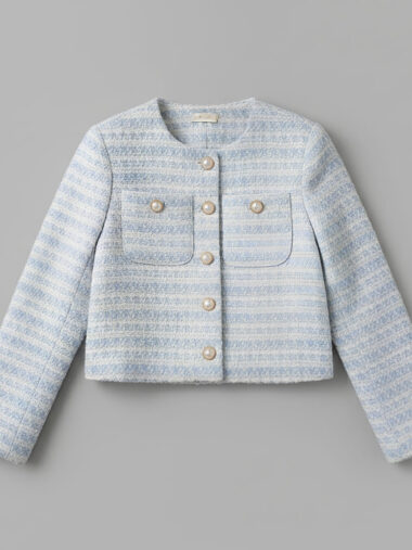 Veste style Chanel femme conception courte et élégante de couleur bleu ciel avec des boutons dorés sur fond gris.