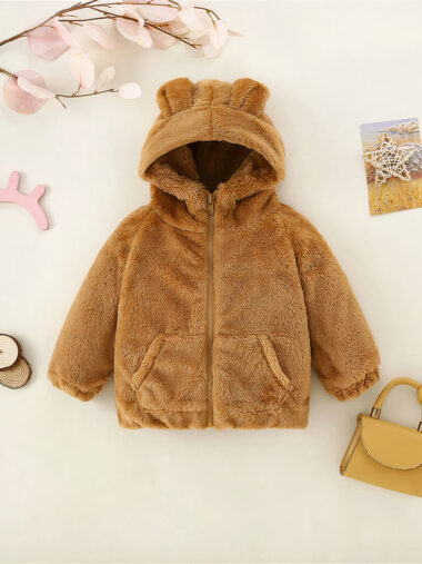 Veste bébé fille chaude avec des oreilles d'ourson avec une branche et des feuilles au-dessus des jouets autour et un sac en bas à droite