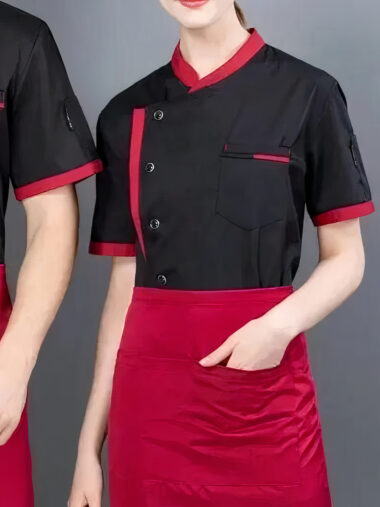 Veste de cuisine femme avec manches courtes et respirantes, de couleur noire avec tablier rouge, porté par une femme.
