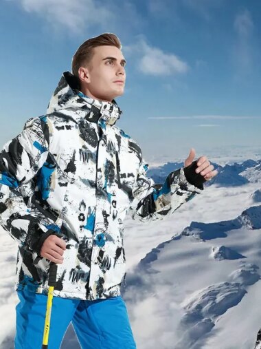 Veste de ski homme avec capuche et imperméable, de couleur blanche, avec du noir et du bleu, porté par un homme, sur un fond avec une montagne enneigée.