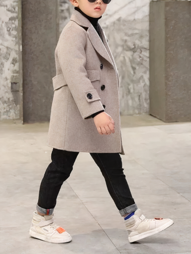 Veste garçon élégante et habillée en laine avec boutons sur un garçon debout sur fond gris