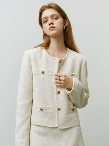 Veste style chanel femme conception courte et douce, de couleur blanche, porté par une femme, sur un fond gris.